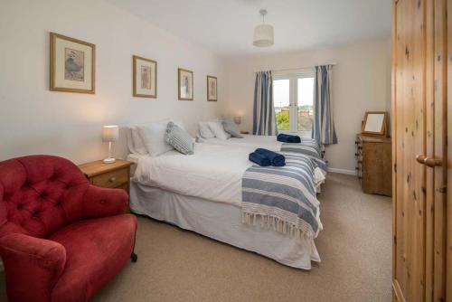 a bedroom with a bed and a red chair at The Green House - 12 Kings Close in Bembridge