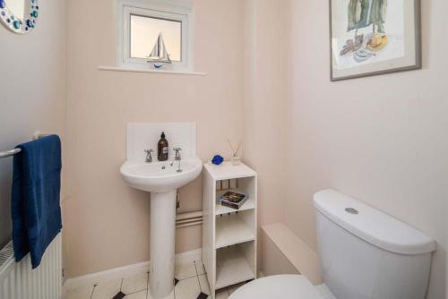 a white bathroom with a sink and a toilet at The Green House - 12 Kings Close in Bembridge