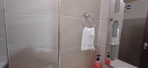 e bagno con doccia e asciugamano bianco sullo scaffale. di B&S Studio apartment, Voi Town a Voi
