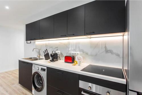 a kitchen with black cabinets and a washer and dryer at Résidence Villette - Buttes Chaumont Botzaris in Paris