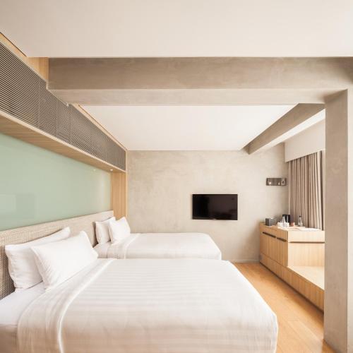 a hotel room with two beds and a television at Ad Lib Hotel Bangkok in Bangkok