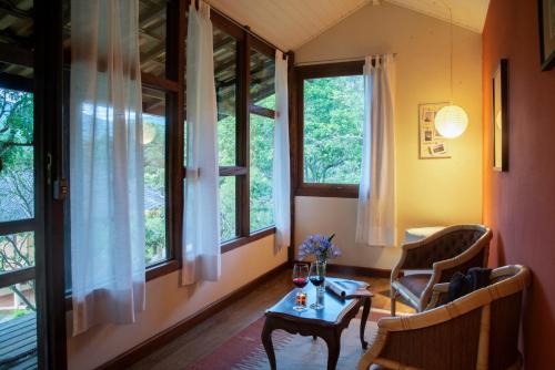 a room with a table and two chairs and windows at Pousada Terra Crua in Visconde De Maua