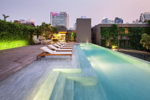 a pool with lounge chairs on top of a building at Ad Lib in Bangkok