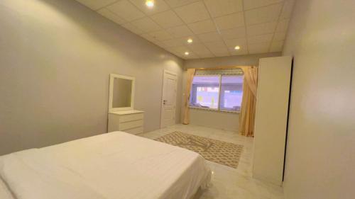 a bedroom with a white bed and a window at شالية ألأمراء 