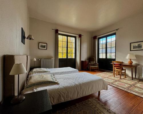 een slaapkamer met een bed, een bureau en 2 ramen bij Maison Etcheverria in Argelès-Gazost