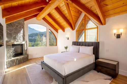 een slaapkamer met een bed en een open haard bij Peak2Peak Chalet - Stunning Log Chalet w/ Mountain Views & Hot Tub - Whistler Platinum in Whistler