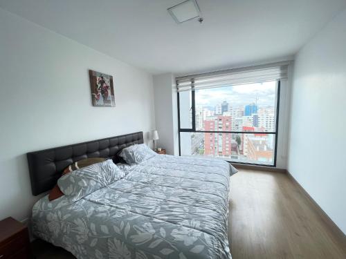 a bedroom with a bed and a large window at Five Stars Suites - Paris - Quito in Quito