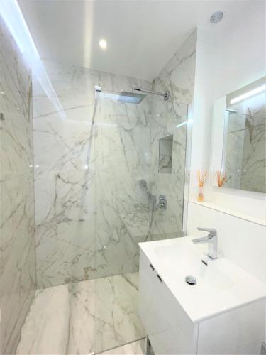 une salle de bain blanche avec une douche et un lavabo dans l'établissement Alba apartment antibes street, by Welcome to Cannes, à Cannes