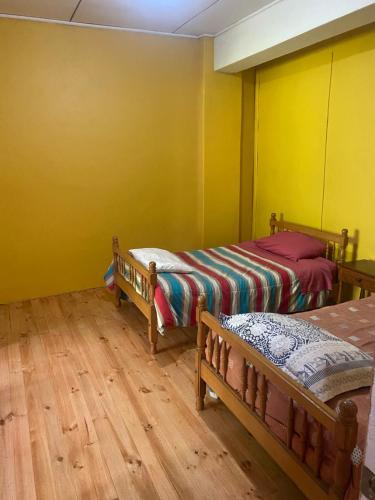 2 camas en una habitación con paredes amarillas y suelo de madera en Hospedaje Vista al Mar 39, en Castro