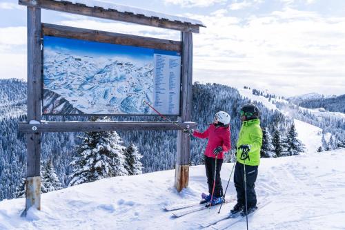 zwei Personen stehen neben einem Schild an einer Skipiste in der Unterkunft PANORAMA SportHOTEL in Folgaria