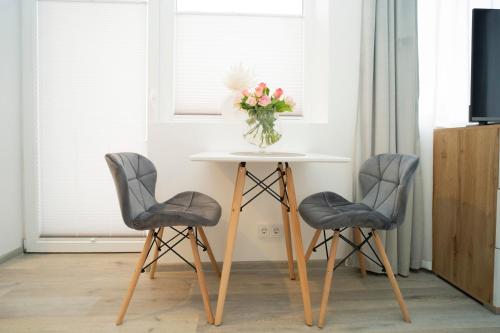 a table with two chairs and a vase of flowers on it at Central Station Apartment No5 in Kaunas