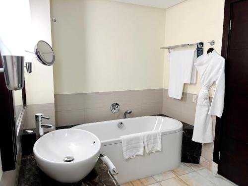 a bathroom with a tub and a sink and towels at Sofitel Al Khobar The Corniche in Al Khobar