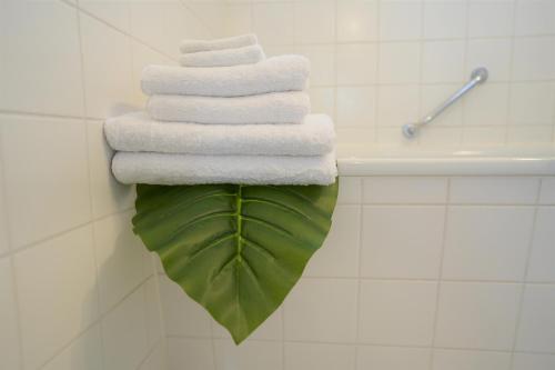 a stack of towels on top of a large green leaf at Fly Inn Apartment Berlin in Schönefeld