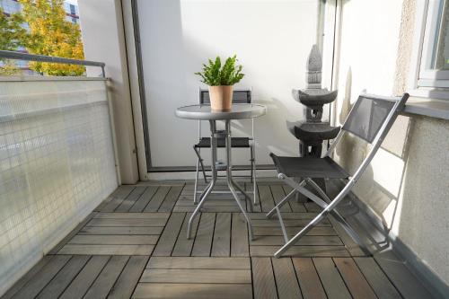 a table and chairs on a balcony with a plant at Fly Inn Apartment Berlin in Schönefeld