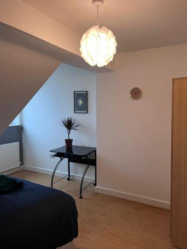 ein Schlafzimmer mit einem Bett und einem Tisch mit einer Lampe in der Unterkunft Westend Villas in Leicester