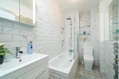 a white bathroom with a sink and a toilet at NIRU Experience Urban Escape 1BR Retreat in London