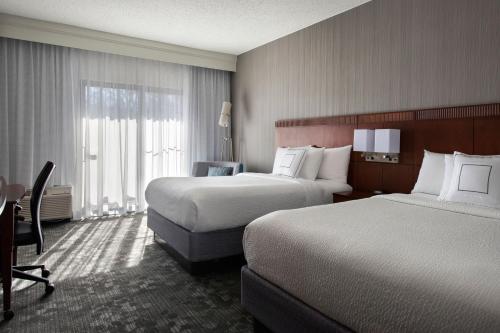 a hotel room with two beds and a window at Courtyard by Marriott Mahwah in Mahwah