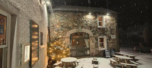 un patio con mesas, un árbol de Navidad y luces en The Herdwick Inn, en Penruddock