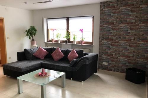 a living room with a black couch and a brick wall at NEU! Ferienwohnung Kippblick Schiffweiler in Schiffweiler