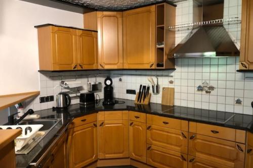 a kitchen with wooden cabinets and black counter tops at NEU! Ferienwohnung Kippblick Schiffweiler in Schiffweiler