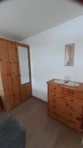 ein leeres Zimmer mit einer hölzernen Kommode und einer Tür in der Unterkunft Ferienwohnung am Querweg in Bockau