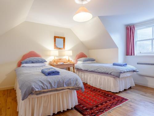 a attic room with two beds and a red rug at 3 bed in Achnasheen CA120 in Inveralligin