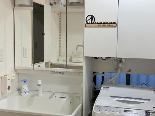 a white kitchen with a sink and a mirror at Asakusa Inn 屋上バルコニー付き100m2広々快適一棟ハウス in Tokyo
