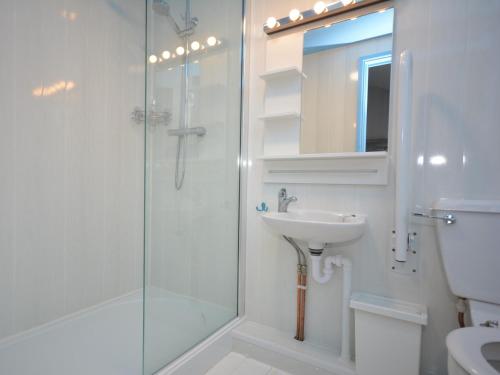 a white bathroom with a shower and a sink at 2 bed in Llansteffan 74268 in Ferryside