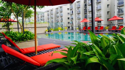 a hotel pool with red chairs and an umbrella at Coco Nest Colombo Sri Lanka in Malabe