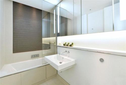 a white bathroom with a sink and a mirror at PARK LANE LARGE LUXURY SLEEPS 6 in London