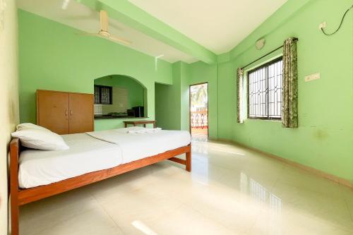 una camera da letto con un letto con pareti verdi e una finestra di Jolene's Mandrem a Mandrem