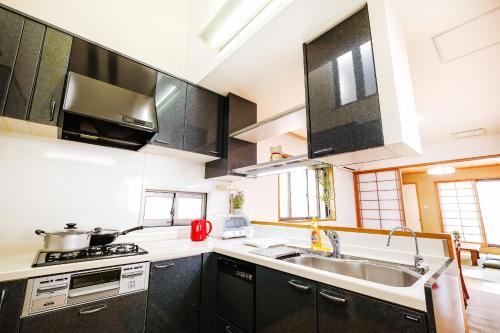 a kitchen with black cabinets and a sink at BBQ!最大14人!駅から5分&有馬温泉直達!長田 in Kobe