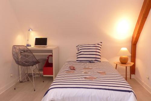 a bedroom with a bed and a laptop on a desk at Ravissante maison traditionnelle bretonne, proche Ria d'Etel in Belz