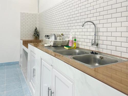 una cocina con fregadero de acero inoxidable y azulejos blancos en Rainhill@Betong en Betong