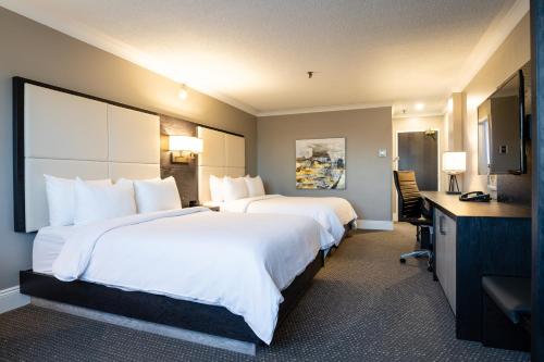 a hotel room with two beds and a desk at Crowne Plaza Hotel Moncton Downtown by IHG in Moncton