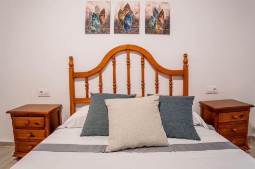 a bed with a wooden headboard and two night stands at Casa Petra in Vejer de la Frontera