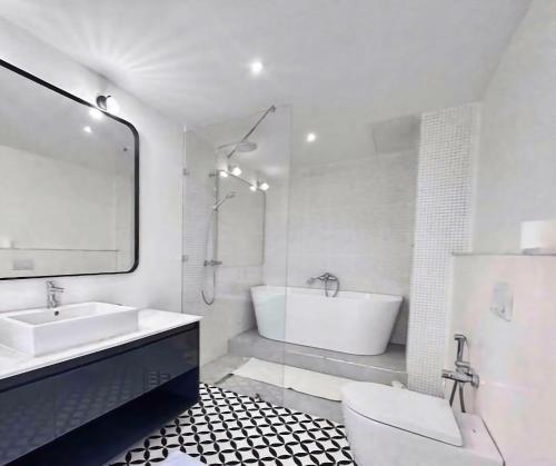 uma casa de banho branca com uma banheira e um lavatório em Triplex luxueux en front de mer. em La Marsa