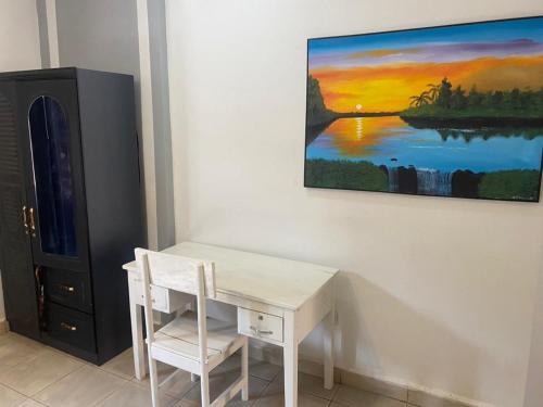 a white desk and chair next to a painting on a wall at KareBer Deluxe - Gulu - Uganda in Gulu