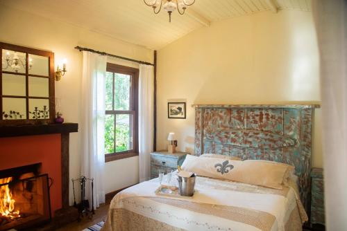 a bedroom with a bed with a headboard and a fireplace at Pousada Terra Crua in Visconde De Maua