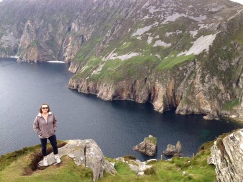 a woman standing on top of a mountain overlooking a body of water at An Uaimh , superb 6 bedroom house. in Killybegs