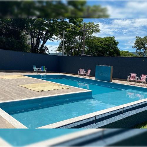 a blue swimming pool with chairs and a fence at Grande Hotel Atibaia in Atibaia