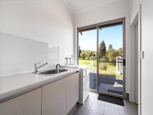 a white kitchen with a sink and a window at The Deck in Margaret River Town