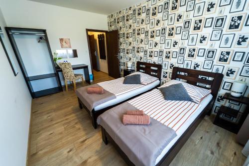 twee bedden in een kamer met een muur met foto's bij Penzion Patron in Brno