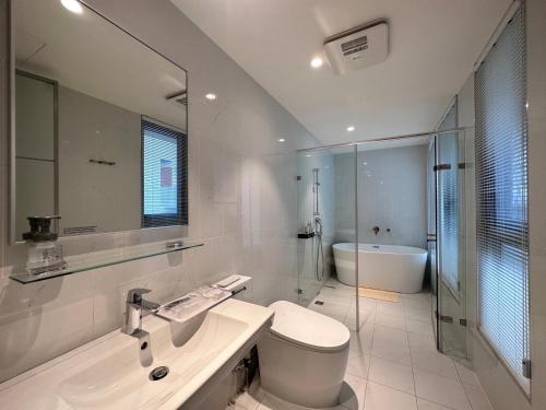 a white bathroom with a toilet and a sink at Yama no Shita Homestay in Zhongpu