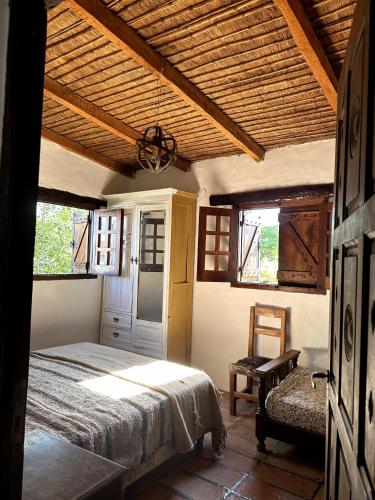 een slaapkamer met een bed, een stoel en ramen bij Casa Los Membrillos in Tafí del Valle
