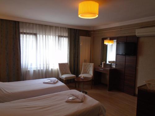 イスタンブールにあるCity Houseのベッド2台とテレビが備わるホテルルームです。