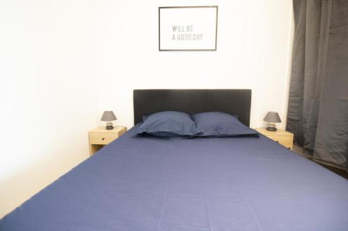 a bedroom with a bed with blue sheets and two lamps at Appartement T2 au centre de Bourg en Bresse in Bourg-en-Bresse