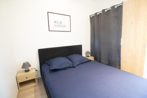 um quarto com uma cama azul e uma cabeceira preta em Appartement T2 au centre de Bourg en Bresse em Bourg-en-Bresse