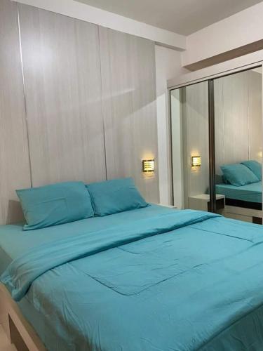 een groot blauw bed met blauwe kussens in een slaapkamer bij SBroomOfficial Apartemen Riverview FREE WIFI AND NETFLIX in Tegalgede