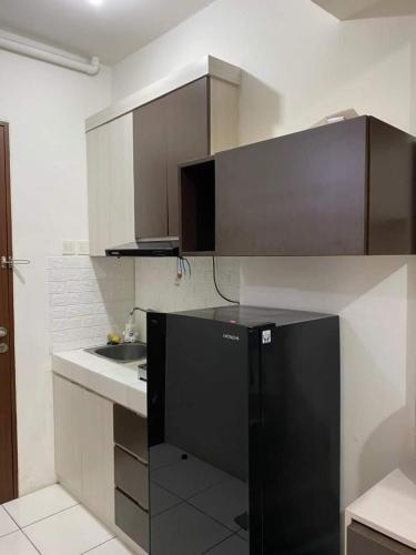een keuken met een zwarte koelkast en een wastafel bij SBroomOfficial Apartemen Riverview FREE WIFI AND NETFLIX in Tegalgede